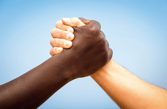Mãos de uma pessoa negra e outra pessoa branca unidas