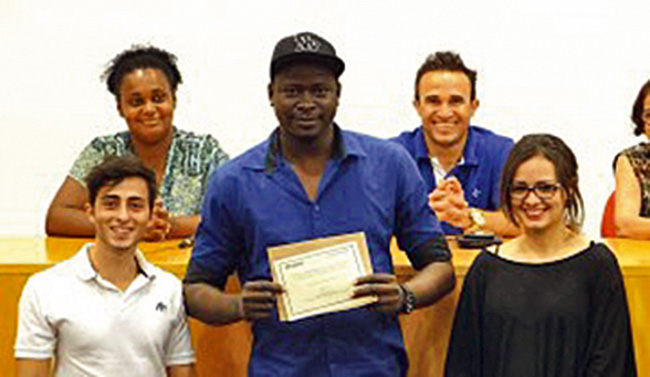 Haitiano mostrando seu diploma, ao lado de membros da UNIMEP