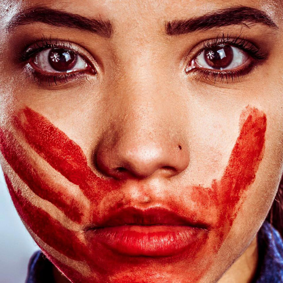 Rosto de uma mulher, com uma mão pintada no rosto em vermelho. Foto de Marcio Freitas | ONG Rio de Paz