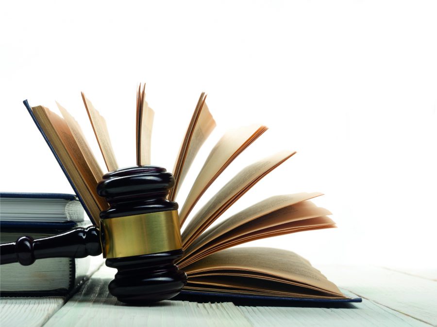 Law concept - Open law book with a wooden judges gavel on table in a courtroom or law enforcement office isolated on white background. Copy space for text.